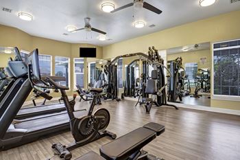 a gym with weights and cardio machines and a large window